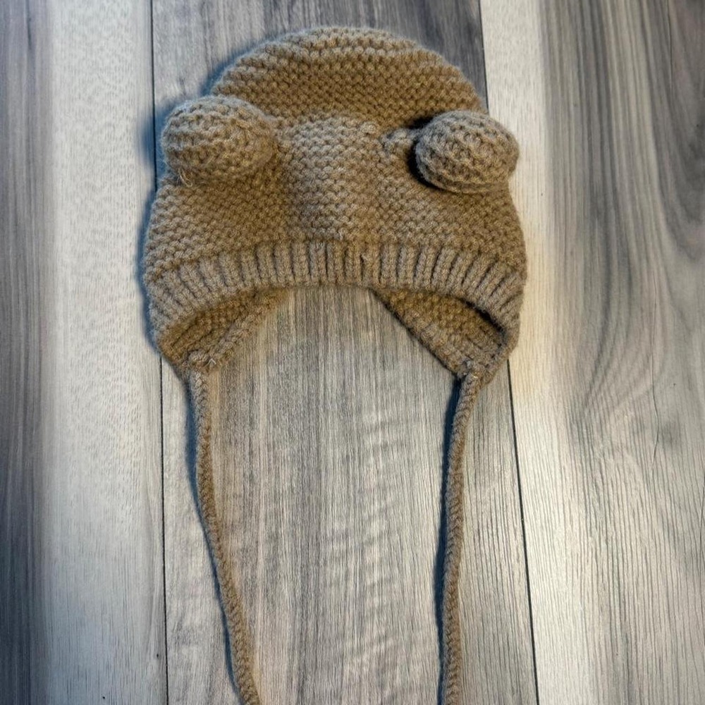 Cozy brown knitted earflap hat with adorable pom-pom details